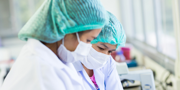 woman in lab wearing masks and hair nets